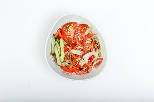 Foto ensalada udon coreana con verduras y carne en un plato sobre un fondo blanco aislado