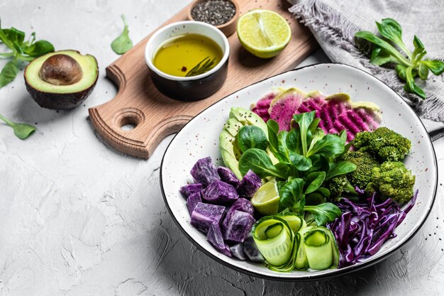 Ensalada vegana con batatas, brócoli, aguacate, repollo morado, pepino, sandía, rábano y almendras.