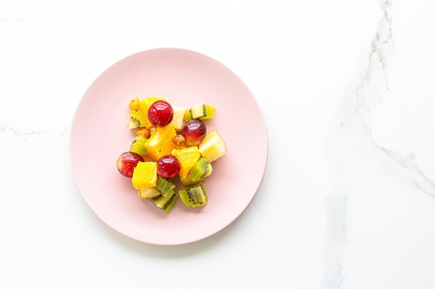 Ensalada vegana de fruta fresca en un plato rosa nutrición saludable y desintoxicación