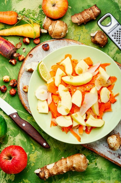 Ensalada vegana natural con jugosa manzana, zanahoria y alcachofa de Jerusalén. Comida dietética.