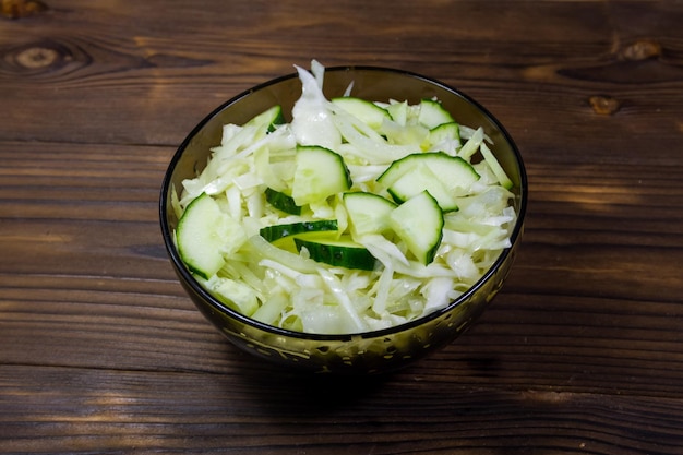 Ensalada vegana de primavera con col y pepino sobre mesa de madera