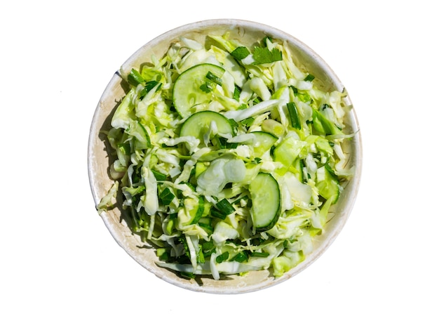 Ensalada vegana de primavera con repollo, pepino, cebolla verde y perejil aislado sobre fondo blanco.