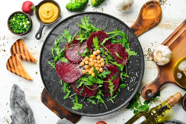 Ensalada vegana remolacha rúcula y garbanzos en un plato de piedra negra Alimentos dietéticos saludables Vista superior Espacio libre para texto