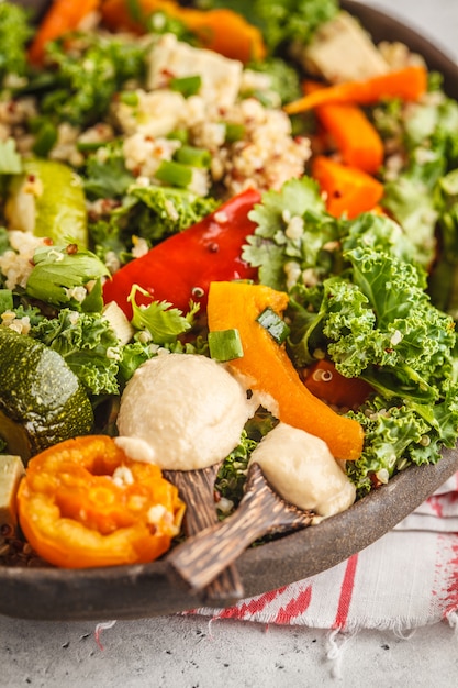 Ensalada vegana saludable con verduras asadas, tahini, quinoa y col rizada. Concepto de alimentación limpia.