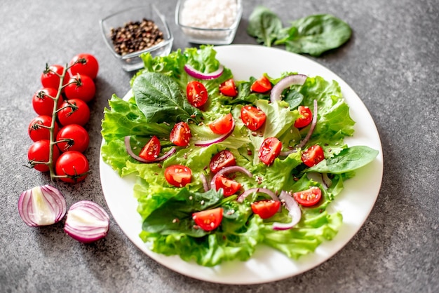 Ensalada vegana verde de verduras y hojas verdes mezcladas sobre fondo de piedraComida saludable