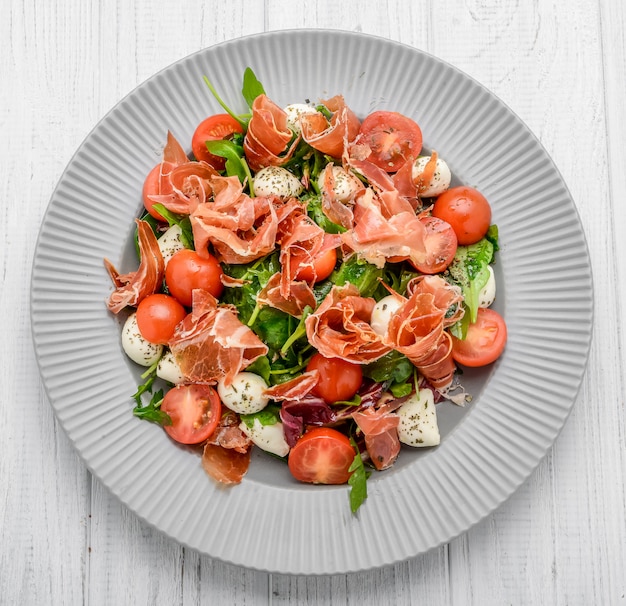 Ensalada de vegetales frescos con tomates secos, carne y mostaza, mozzarella, jamón serrano