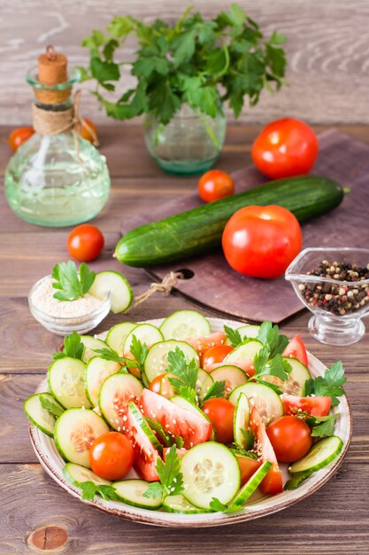 Ensalada de vegetales de pepinos frescos, tomates, perejil y semillas de sésamo en un plato sobre una mesa de madera.