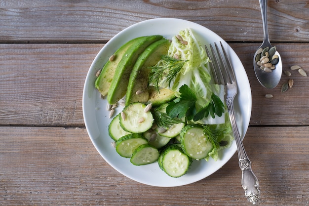 Ensalada de vegetales saludables de pepino fresco, aguacate, lechuga y semillas en placa