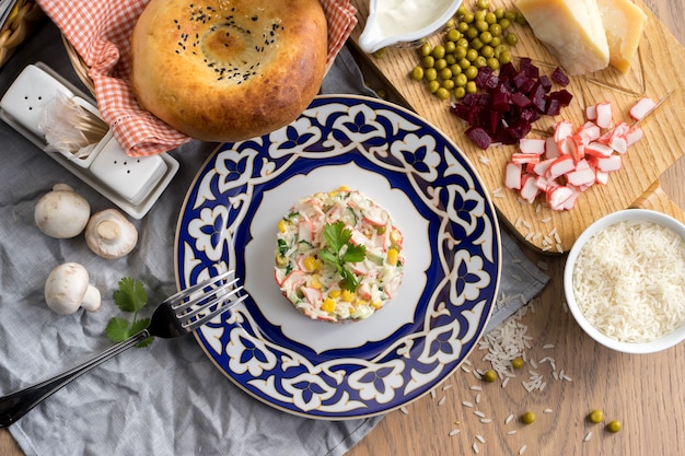 Ensalada vegetariana con arroz, pepino, maíz y palitos de cangrejo en un plato con un tradicional uzbeko