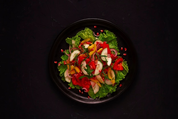 Ensalada vegetariana fresca, hecha de verduras, sobre un fondo negro, vista superior de nutrición adecuada, sin gente, horizontal. Foto de alta calidad