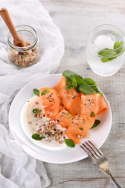 Foto ensalada vegetariana sin gluten con zanahoria y yogur sazonada con frutos secos triturados y especias, coladas de menta