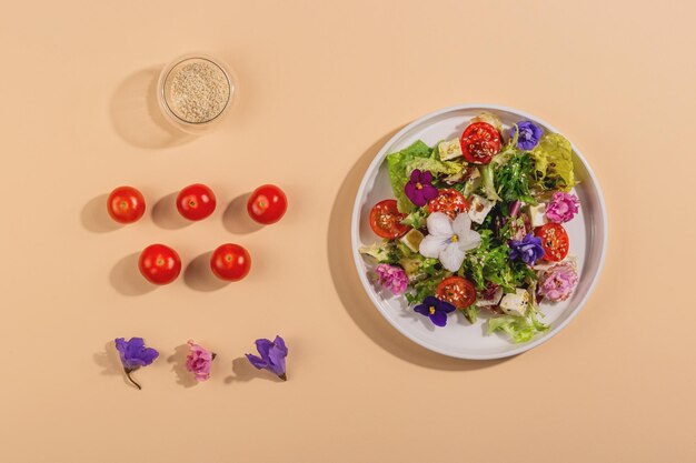 Ensalada vegetariana con lechuga de tomate y queso adornada con flores comestibles en la luz dura