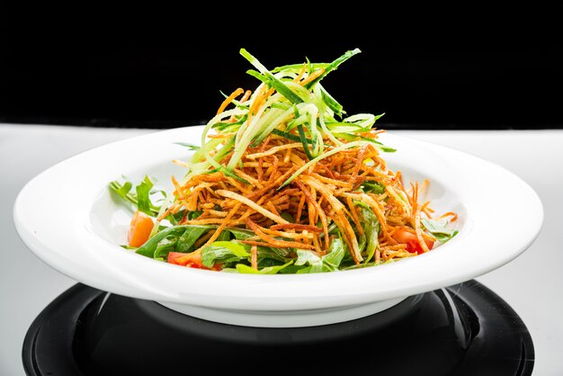 Ensalada vegetariana con papas fritas y rúcula en un plato