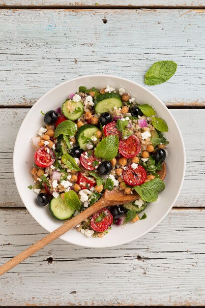 Ensalada vegetariana de quinua, tomates, pepinos, garbanzos, aceitunas, hierbas, requesón