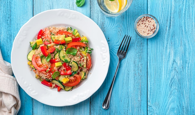 Ensalada vegetariana con quinua, verduras frescas y hierbas sobre un fondo de madera azul Vista superior espacio de copia