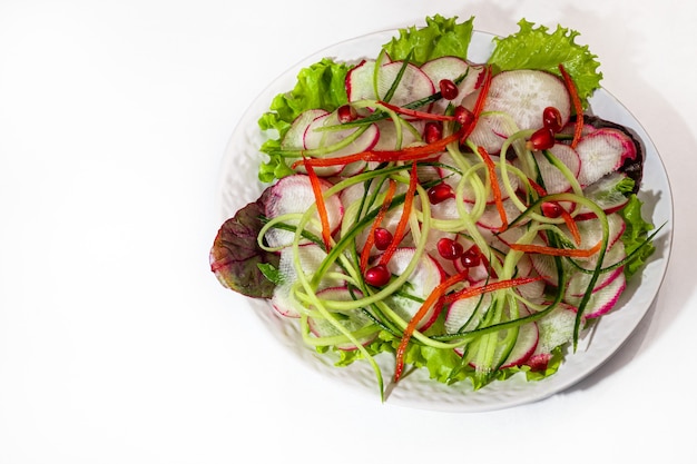 Ensalada vegetariana de rábano, espinacas, cebolla morada y pimiento morrón y pepino. Sobre un fondo claro. Copie el espacio.