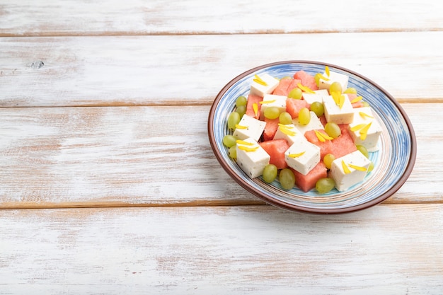 Ensalada vegetariana con sandía, queso feta y uvas en placa de cerámica azul