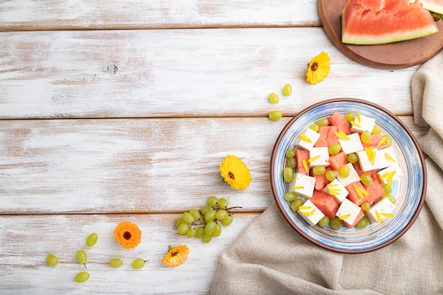 Ensalada vegetariana con sandía, queso feta y uvas en placa de cerámica azul