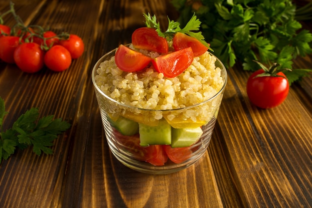 Ensalada vegetariana con verduras y quinua en la mesa de madera marrón