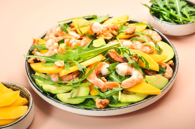 Ensalada de verano con camarones con mango y aguacate, nuez, espinacas y rúcula Concepto de alimentación saludable Vista superior fondo rosa