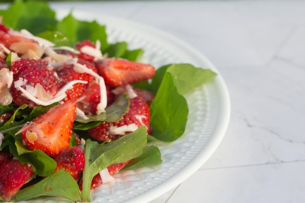 Ensalada de verano con fresas en un plato blanco y un fondo claro Cerrar Lugar para copiar espacio