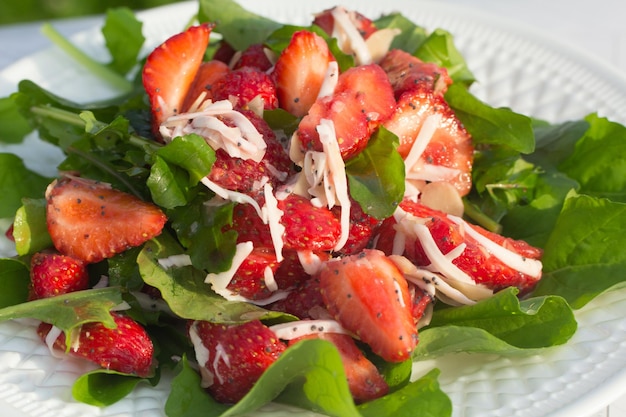 Ensalada de verano con fresas en un plato blanco y un fondo claro Cerrar