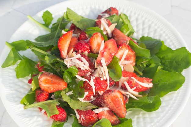 Ensalada de verano con fresas en un plato blanco y un fondo claro Lugar para copiar