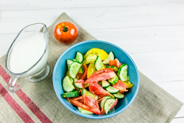 Ensalada de verano con pepinos y tomates sobre fondo blanco.