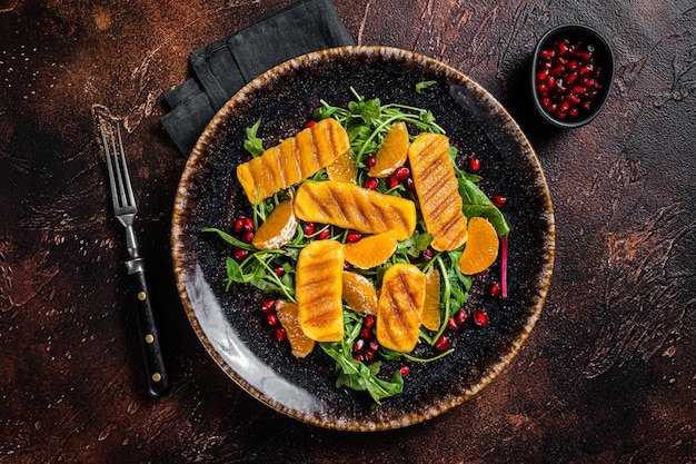 Ensalada de verano con queso Halloumi a la parrilla, naranjas de rúcula y granada Fondo oscuro Vista superior