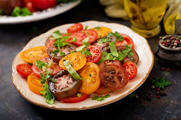 Ensalada de verano de tomates de diferentes colores con hierbas verdes y pimienta.