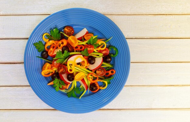 Ensalada de verano con tomates en plato blanco sobre mesa de madera