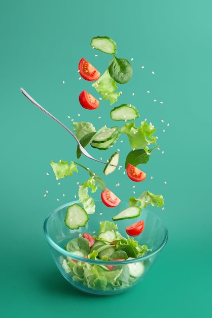 Foto ensalada verde cayendo en un plato sobre un fondo verde