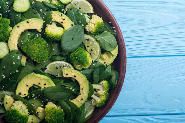 Ensalada verde de espinacas tiernas con aguacate, brócoli, pepino, lima y sésamo, comida vegana desintoxicante saludable