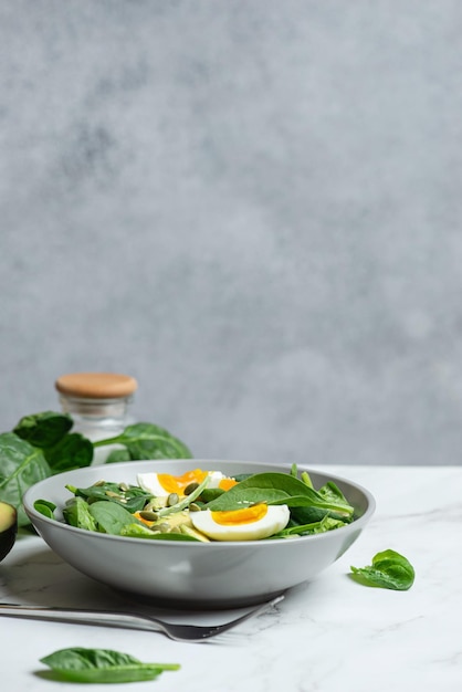 Ensalada verde fresca con aguacate de huevo y espinacas sobre un fondo gris en un plato gris