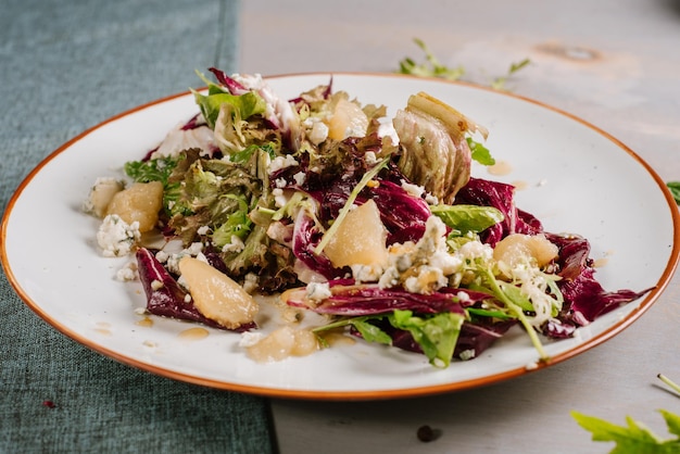 Ensalada verde con frutas, verduras y hierbas en el fondo de madera