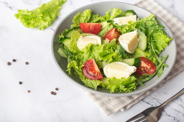 ensalada verde con mozzarella sobre fondo de piedra gris