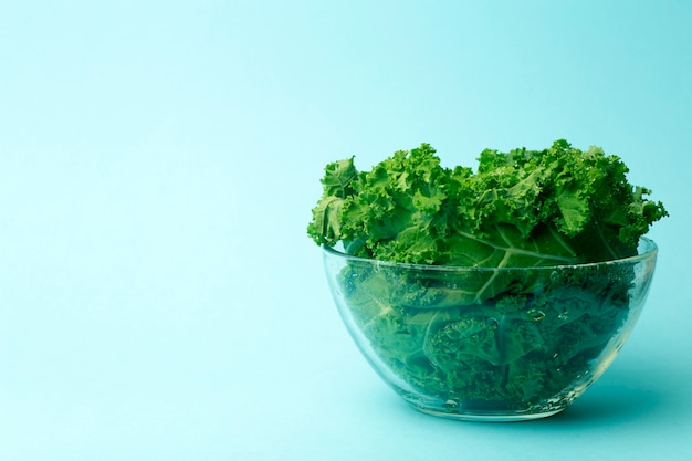 Ensalada verde en un recipiente de vidrio en azul