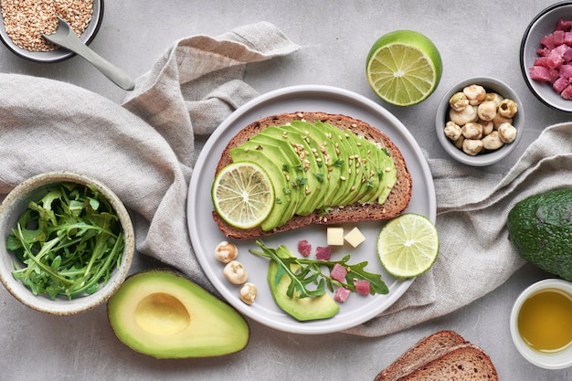 Ensalada verde y sandwich de aguacate, vista superior en piedra gris