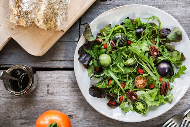 Ensalada verde con tomates verdes, nueces y bayas de Goji con aderezo balsámico y pan francés