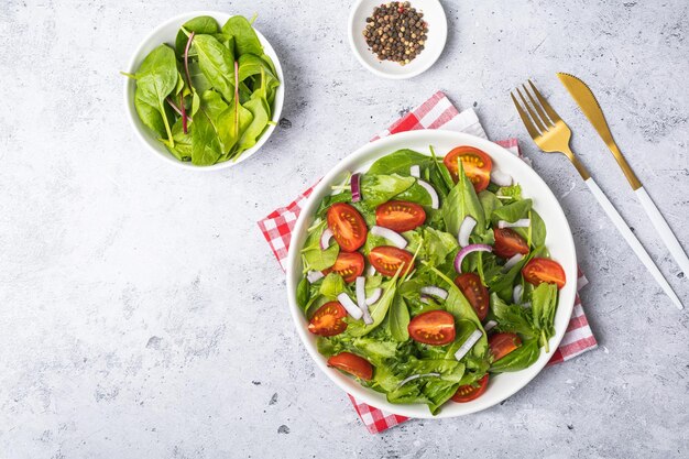 Ensalada verde de verano en plato blanco sobre mesa gris