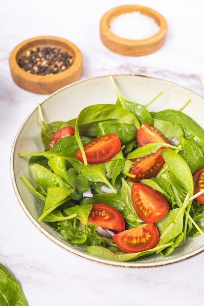 Foto ensalada verde de verano en plato blanco sobre mesa gris