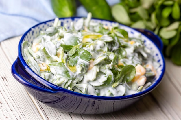 Ensalada de verdolaga con yogur en un recipiente sobre fondo de madera.