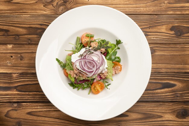 Ensalada de verduras con atún, espárragos y huevo escalfado en una placa de cerámica blanca