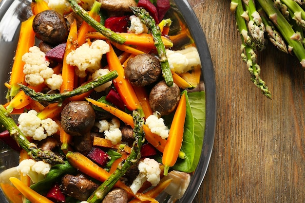 Ensalada de verduras con champiñones y zanahorias baby en la vista superior de la mesa de madera