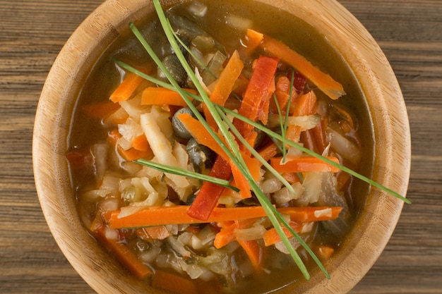 Foto ensalada de verduras en escabeche picadas en un tazón redondo mezclado con aceite. alimentos fermentados saludables en la vista superior de la mesa de madera