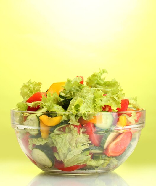 Ensalada de verduras frescas en un cuenco transparente sobre un fondo verde
