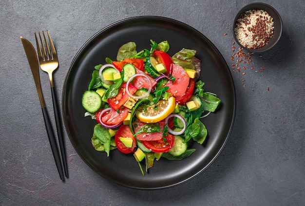 Ensalada de verduras frescas con hierbas frescas de salmón y semillas sobre un fondo oscuro