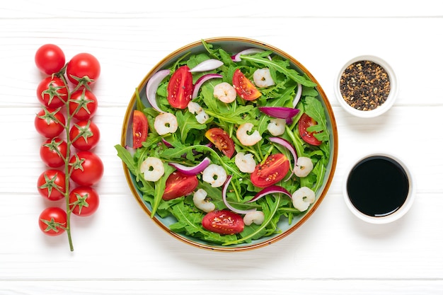 Ensalada de verduras frescas en plato sobre mesa de madera blanca