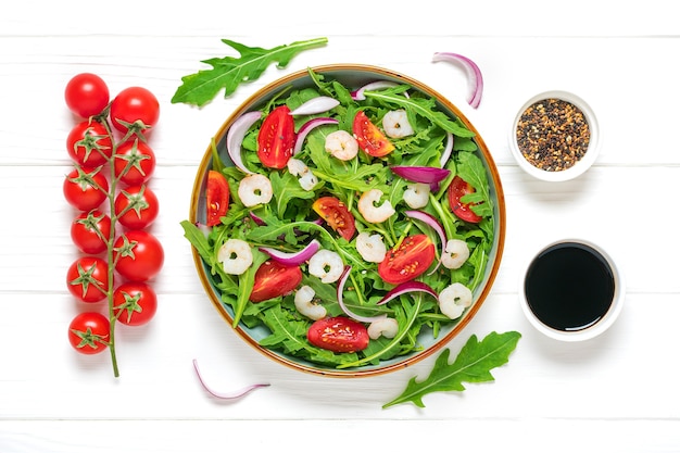 Ensalada de verduras frescas en plato sobre mesa de madera blanca