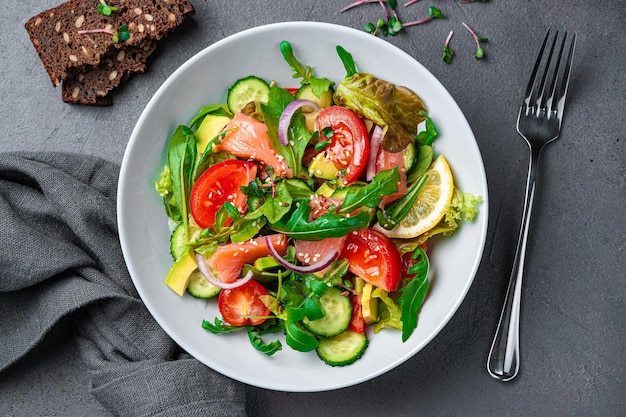 Ensalada de verduras con hierbas frescas de salmón y limón sobre un fondo oscuro Vista superior primer plano Alimentos saludables